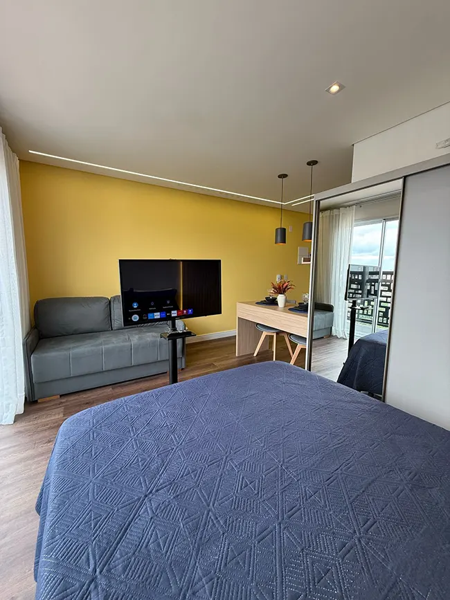 Studio Mobilité Righeto — sala integrada com parede amarela e vista da cidade